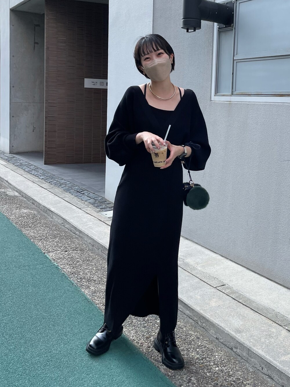 ブラック系のワンピース、ブラック系のブーツ、グリーン系のショルダーバッグを着用したレディースの秋コーディネートの2枚目の写真