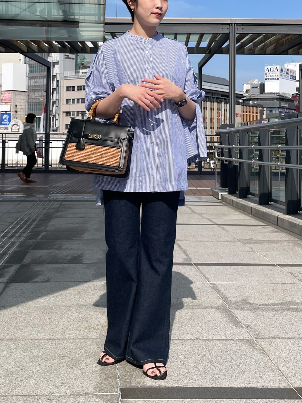 ブルー系のシャツ/ブラウス、ブルー系のデニムパンツ、ブラック系のハンドバッグを着用したレディースの春コーディネートの2枚目の写真