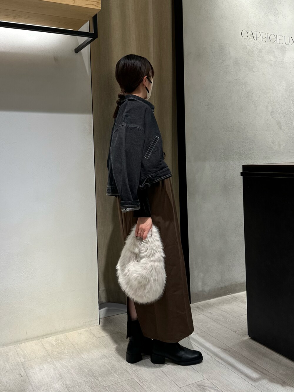 ブラック系のワンピース、ブラック系のブルゾン、ホワイト系のハンドバッグを着用したレディースの秋コーディネートの2枚目の写真