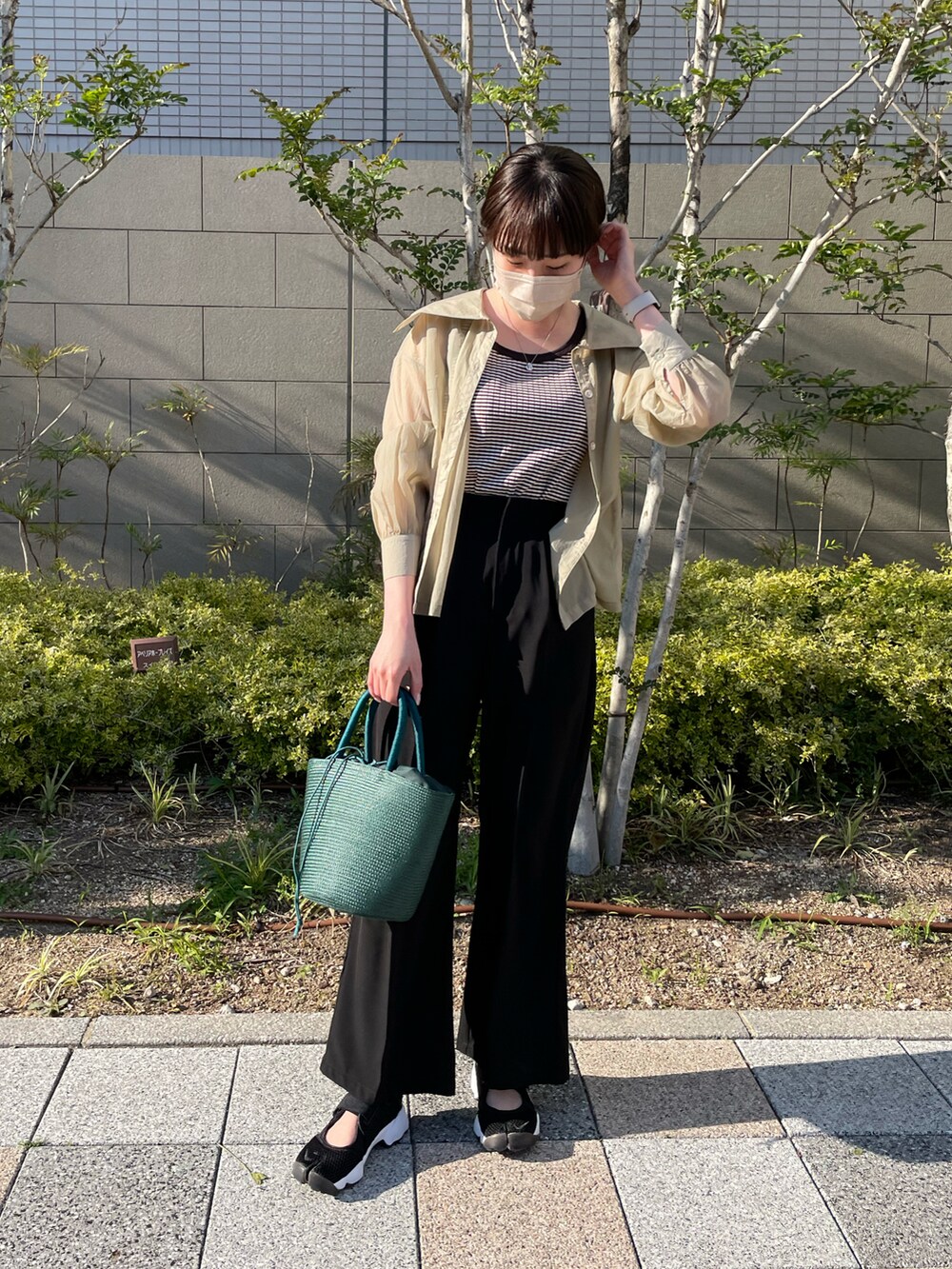 グリーン系のシャツ/ブラウス、ブラウン系のタンクトップ、ホワイト系のハンドバッグを着用したレディースの春コーディネートの2枚目の写真