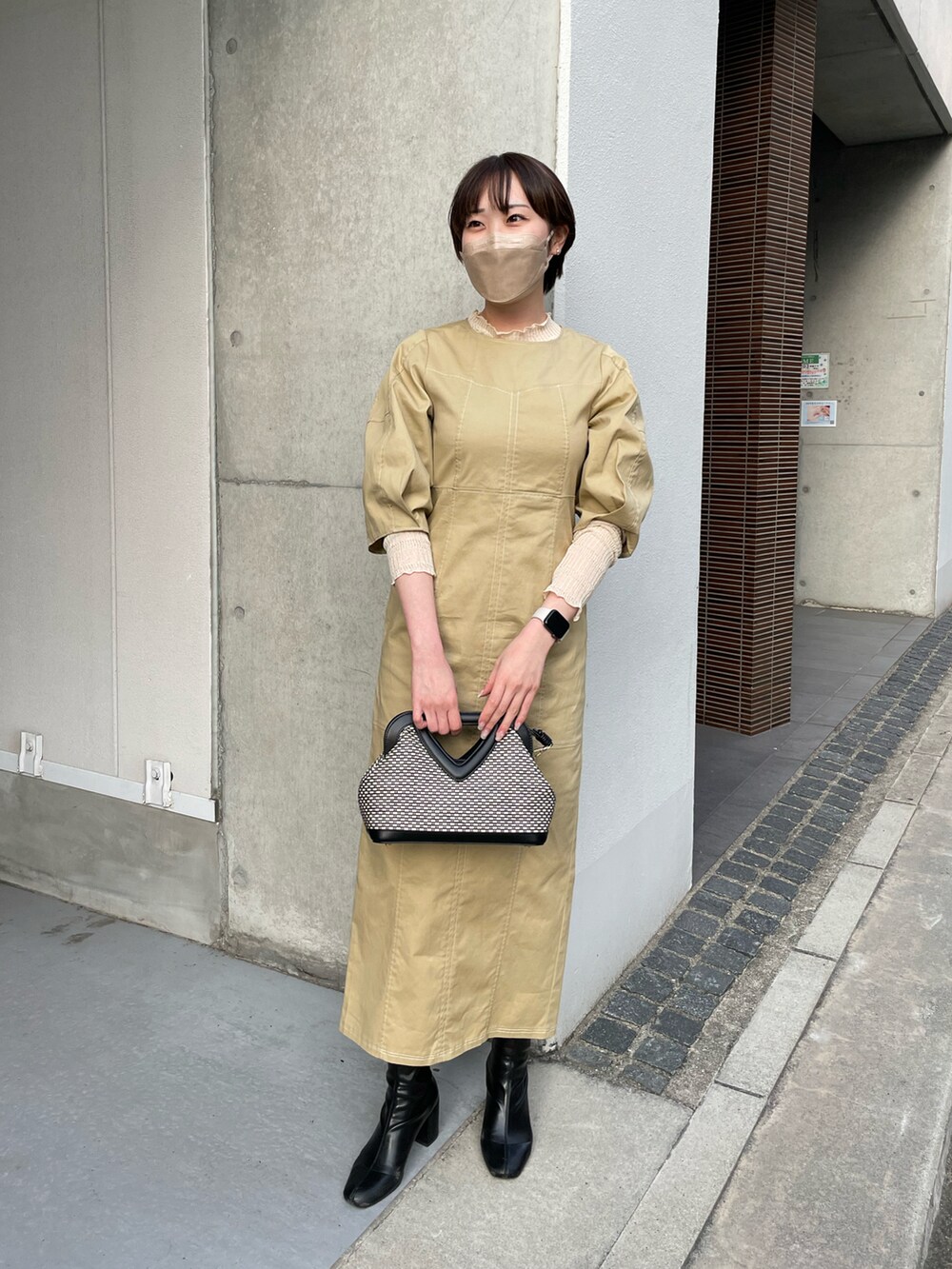 ベージュ系のワンピース、ホワイト系のニット/セーター、ブラック系のショルダーバッグを着用したレディースの春コーディネートの2枚目の写真