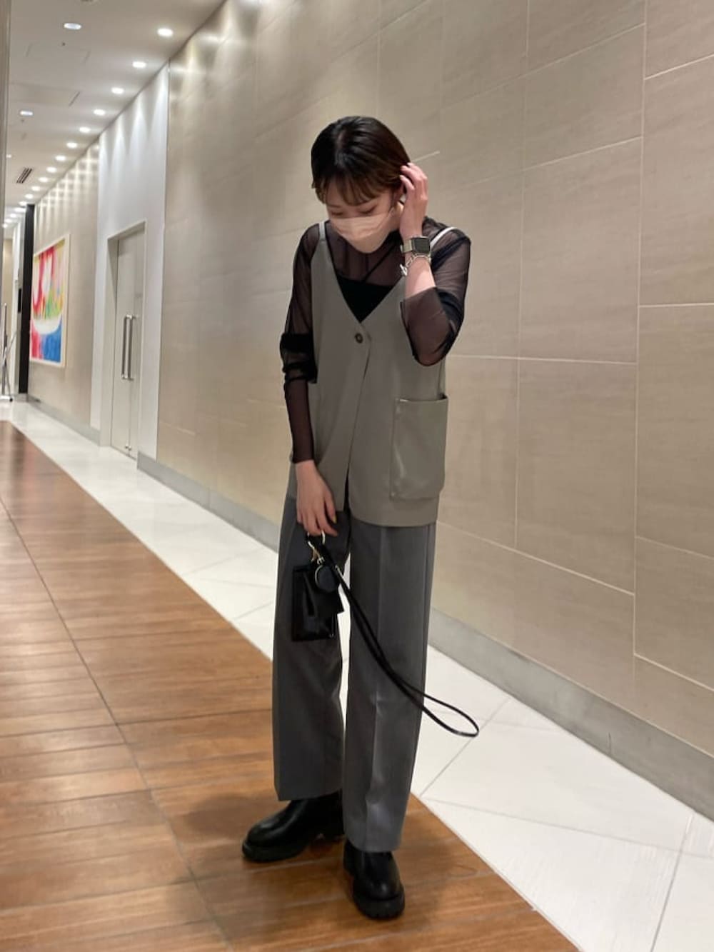 ベージュ系のベスト、グレー系のスラックス、ブラック系のブーツを着用したレディースの秋コーディネートの2枚目の写真