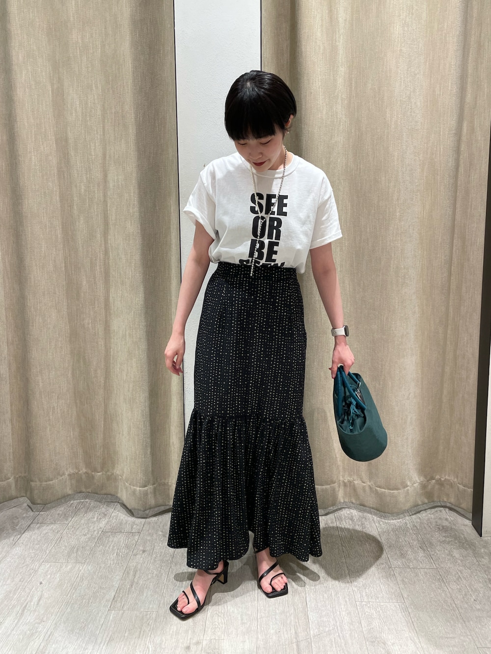 ホワイト系のTシャツ/カットソー、ブラック系のスカートを着用したレディースの春コーディネートの2枚目の写真