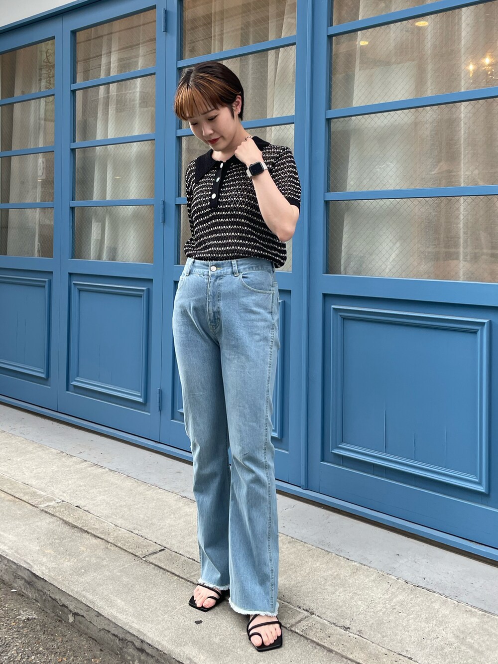 ブラック系のニット/セーター、ブルー系のデニムパンツ、ホワイト系のサンダルを着用したレディースの夏コーディネートの3枚目の写真