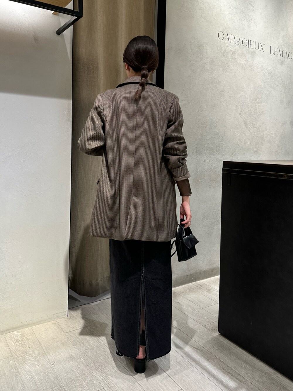 ブラウン系のテーラードジャケット、ブラウン系のニット/セーター、ブラック系のデニムスカートを着用したレディースの秋コーディネートの2枚目の写真