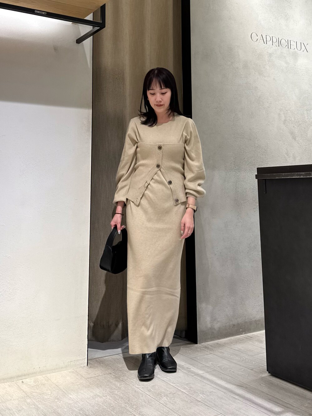 ベージュ系のワンピース、ベージュ系のテーラードジャケット、ブラック系のショルダーバッグを着用したレディースの冬コーディネートの2枚目の写真