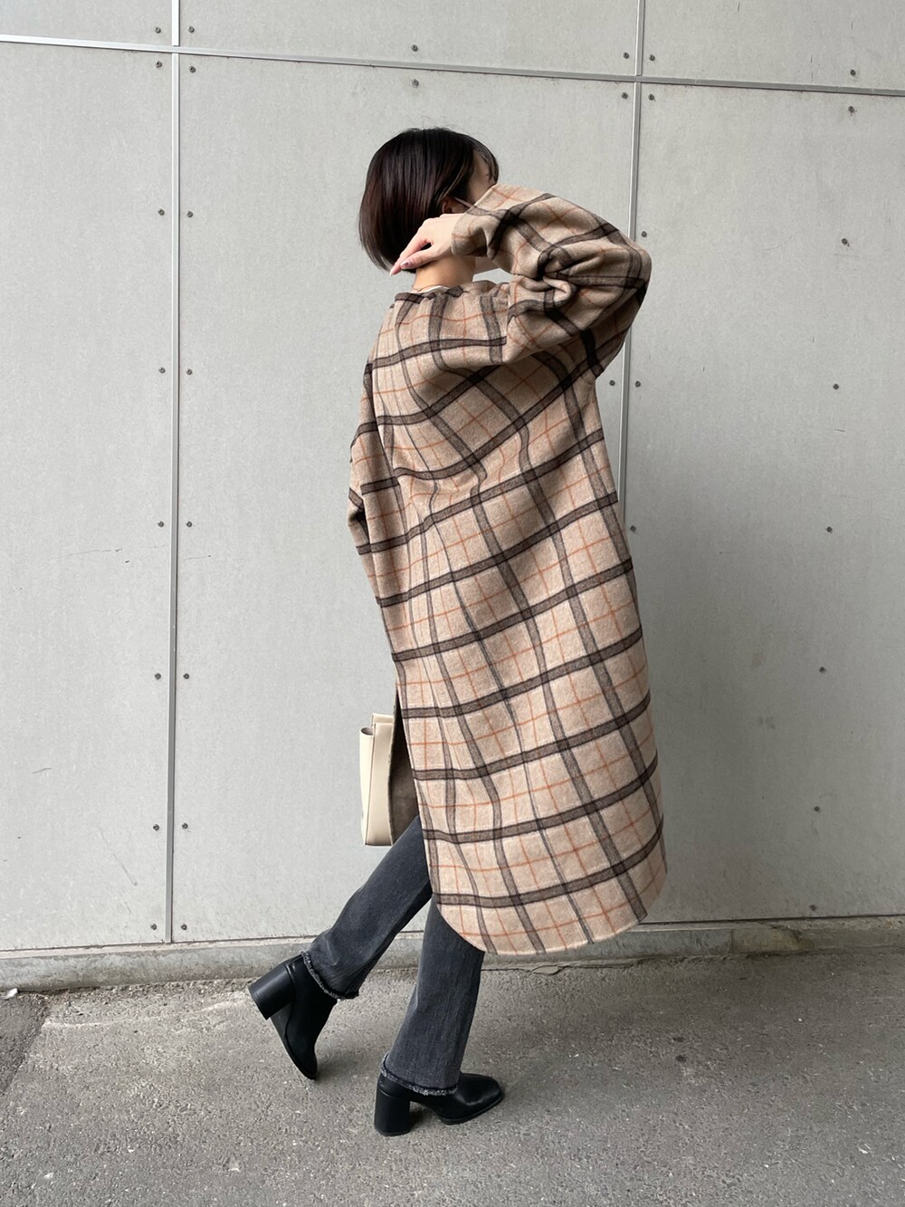 ブラック系のデニムパンツ、ベージュ系のノーカラーコートを着用したレディースの秋コーディネートの2枚目の写真