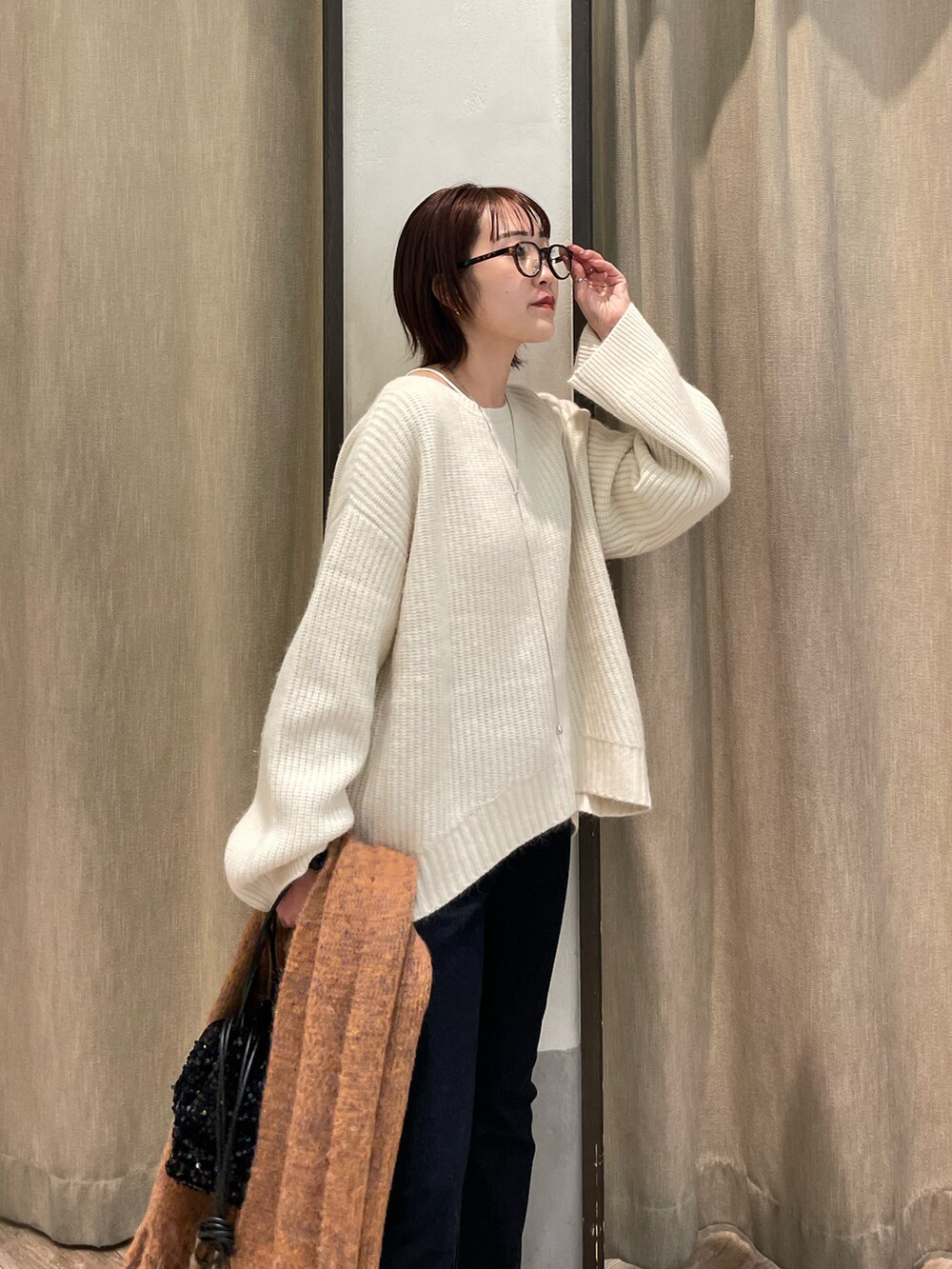 ホワイト系のニット/セーター、ブルー系のデニムパンツ、オレンジ系のマフラーを着用したレディースの秋コーディネートの2枚目の写真