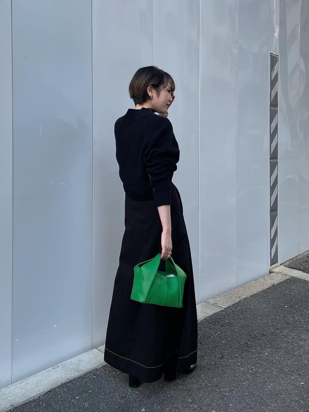 ブラック系のスカート、グリーン系のハンドバッグ、ブラック系のニット/セーターを着用したレディースの冬コーディネートの2枚目の写真