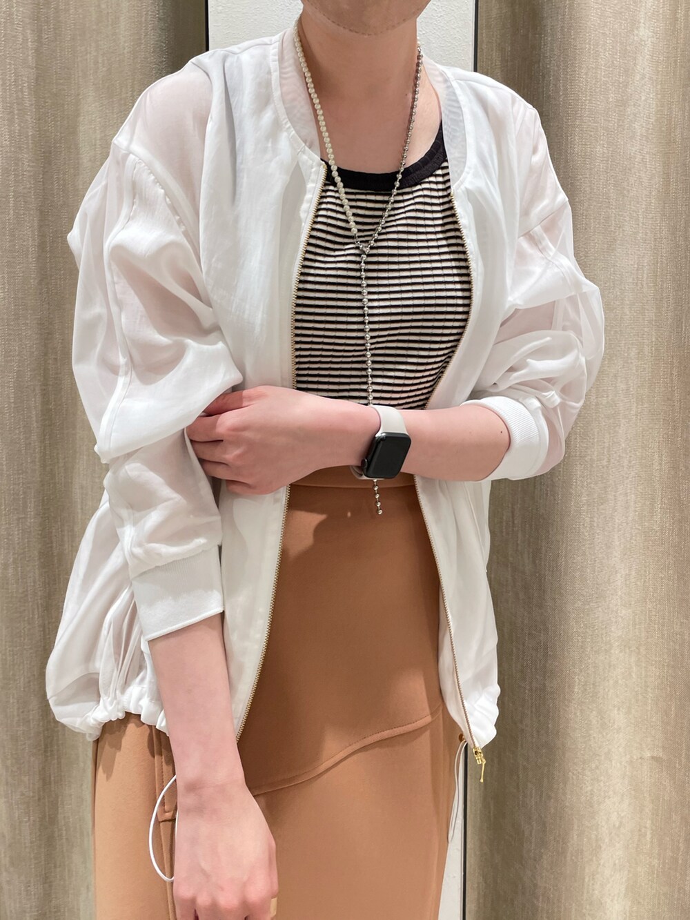 ブラウン系のTシャツ/カットソー、ホワイト系のブルゾン、オレンジ系のスカートを着用したレディースの春コーディネートの3枚目の写真