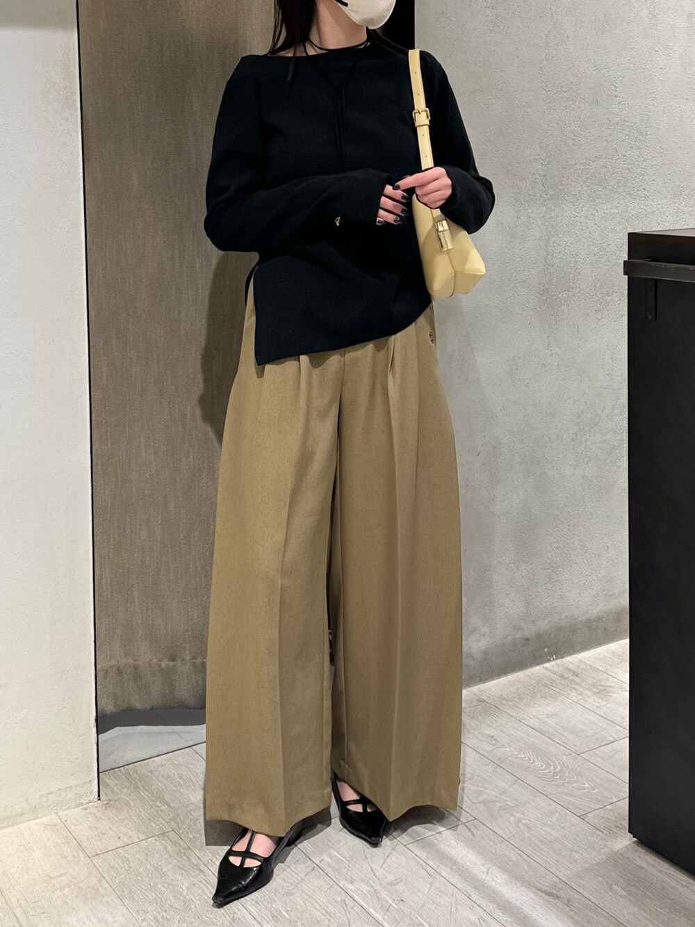 ブラック系のニット/セーター、ベージュ系のその他パンツ、ホワイト系のショルダーバッグを着用したレディースの秋コーディネートの2枚目の写真