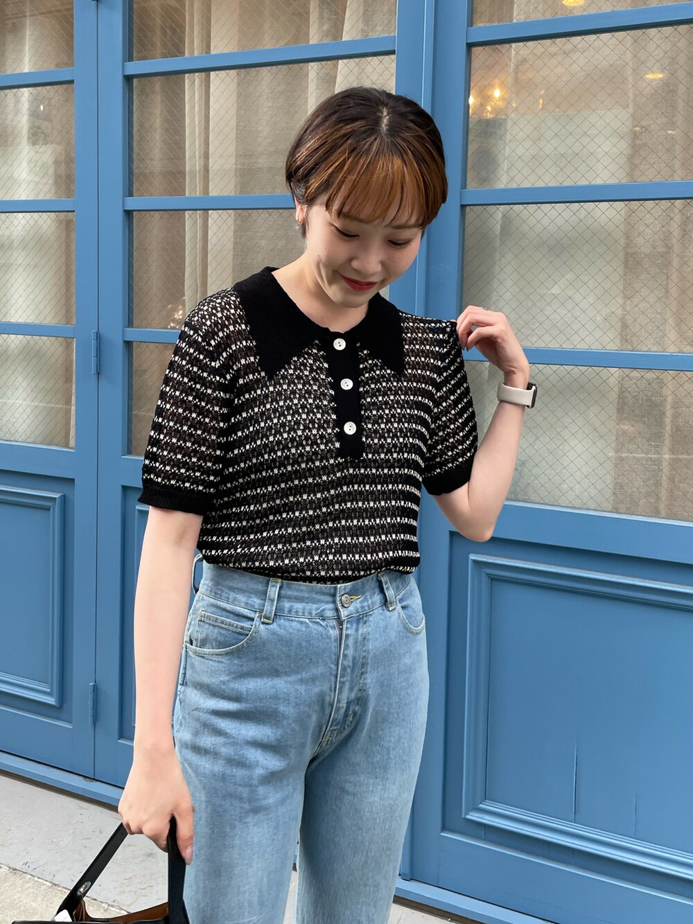 ブラック系のニット/セーター、ブルー系のデニムパンツ、ホワイト系のサンダルを着用したレディースの夏コーディネートの4枚目の写真