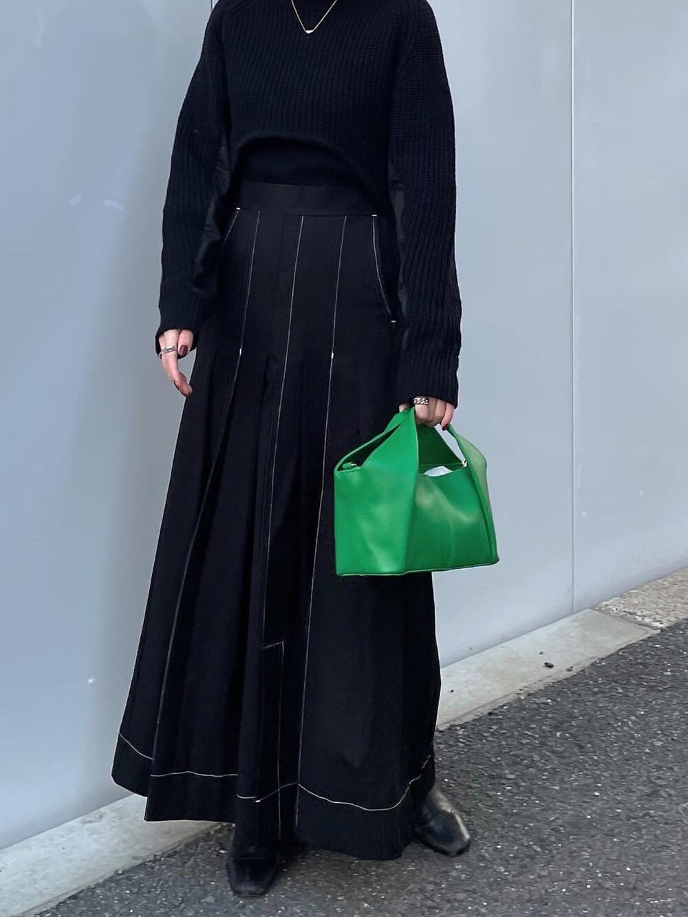 ブラック系のスカート、グリーン系のハンドバッグ、ブラック系のニット/セーターを着用したレディースの冬コーディネートの3枚目の写真