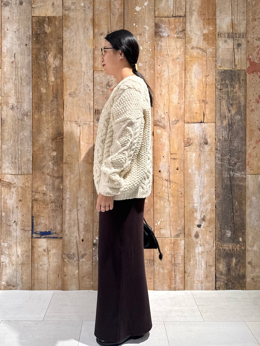 ホワイト系のニット/セーター、ブラウン系のスカート、ブラック系のショルダーバッグを着用したレディースの秋コーディネートの2枚目の写真
