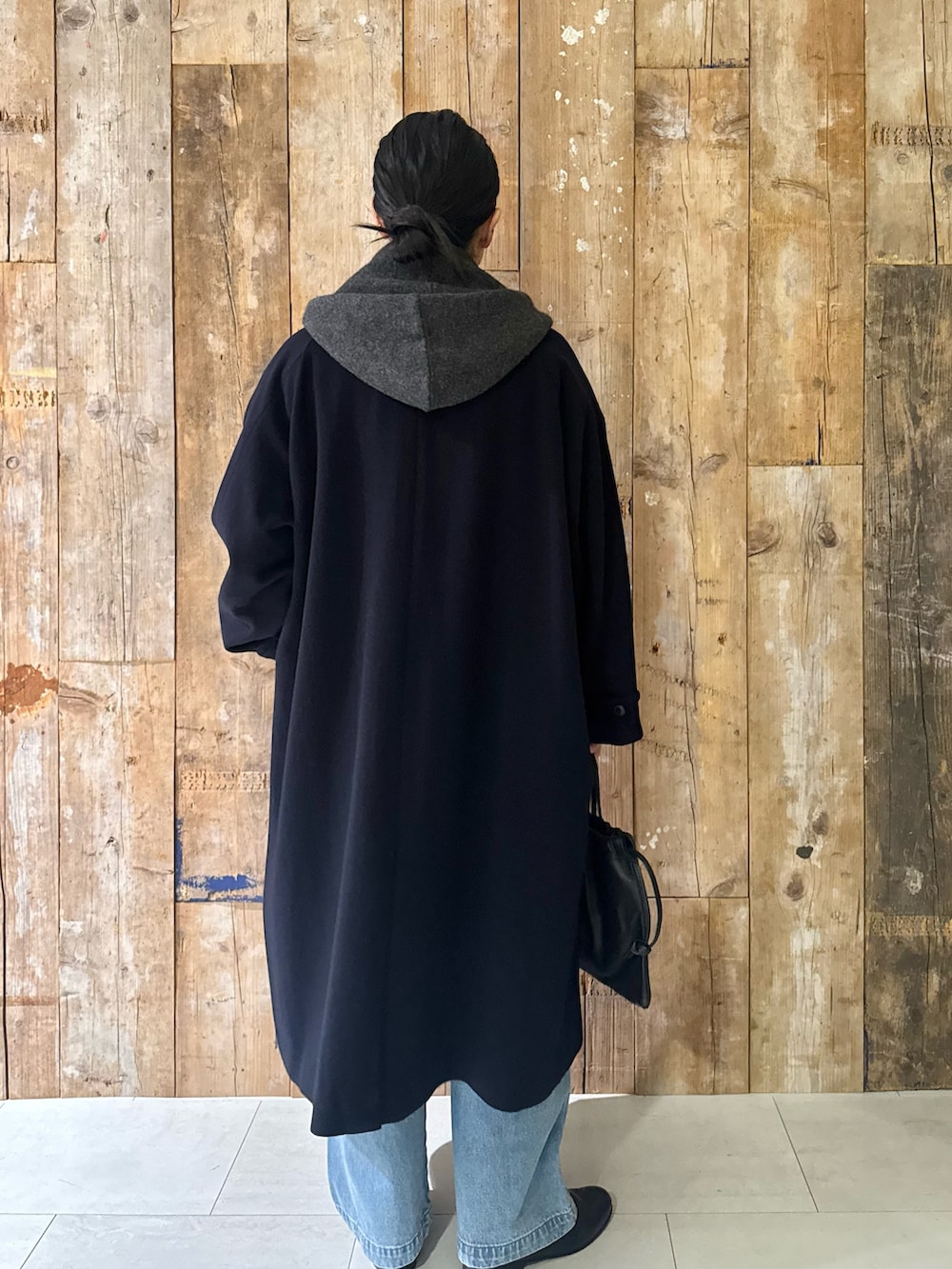 ブルー系のステンカラーコート、ブルー系のデニムパンツ、グリーン系のニット/セーターを着用したレディースの冬コーディネートの2枚目の写真