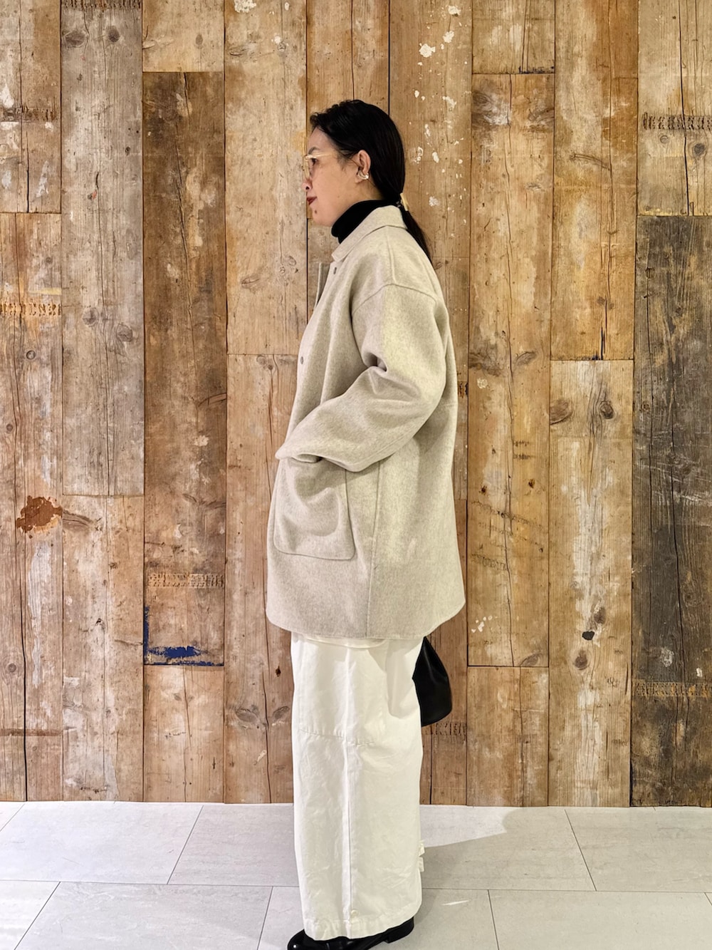 ベージュ系のその他アウター、ブラック系のニット/セーター、ホワイト系のその他パンツを着用したレディースの秋コーディネートの2枚目の写真