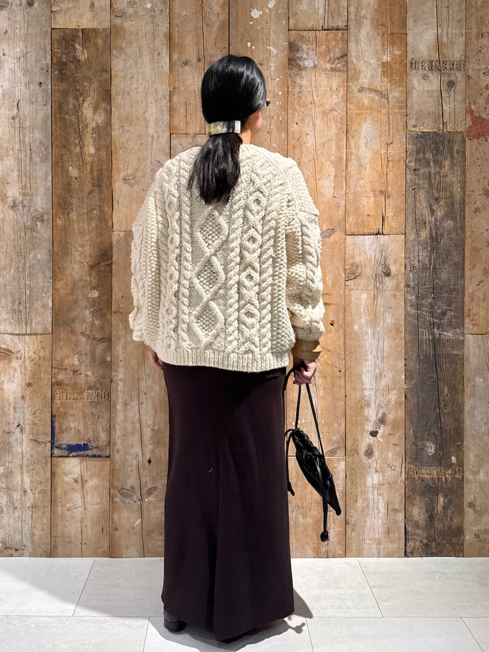 ホワイト系のニット/セーター、ブラウン系のスカート、ブラック系のショルダーバッグを着用したレディースの秋コーディネートの3枚目の写真