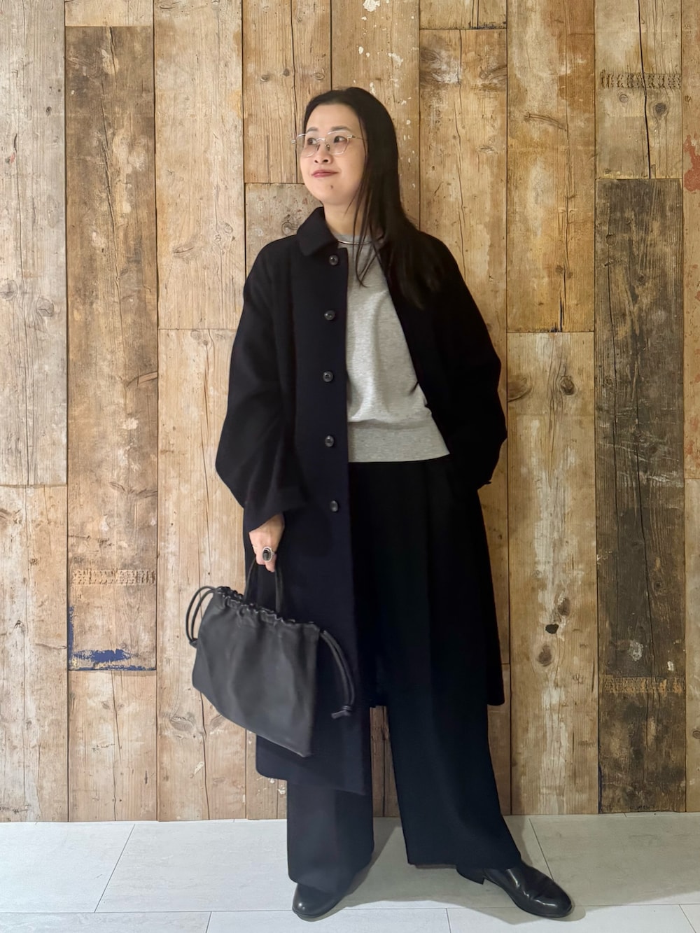 ブルー系のステンカラーコート、グレー系のTシャツ/カットソー、ブラック系のその他パンツを着用したレディースの冬コーディネートの2枚目の写真