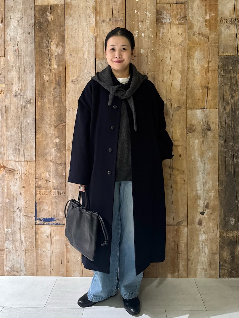 ブルー系のステンカラーコート、ブルー系のデニムパンツ、グリーン系のニット/セーターを着用したレディースの冬コーディネートの3枚目の写真