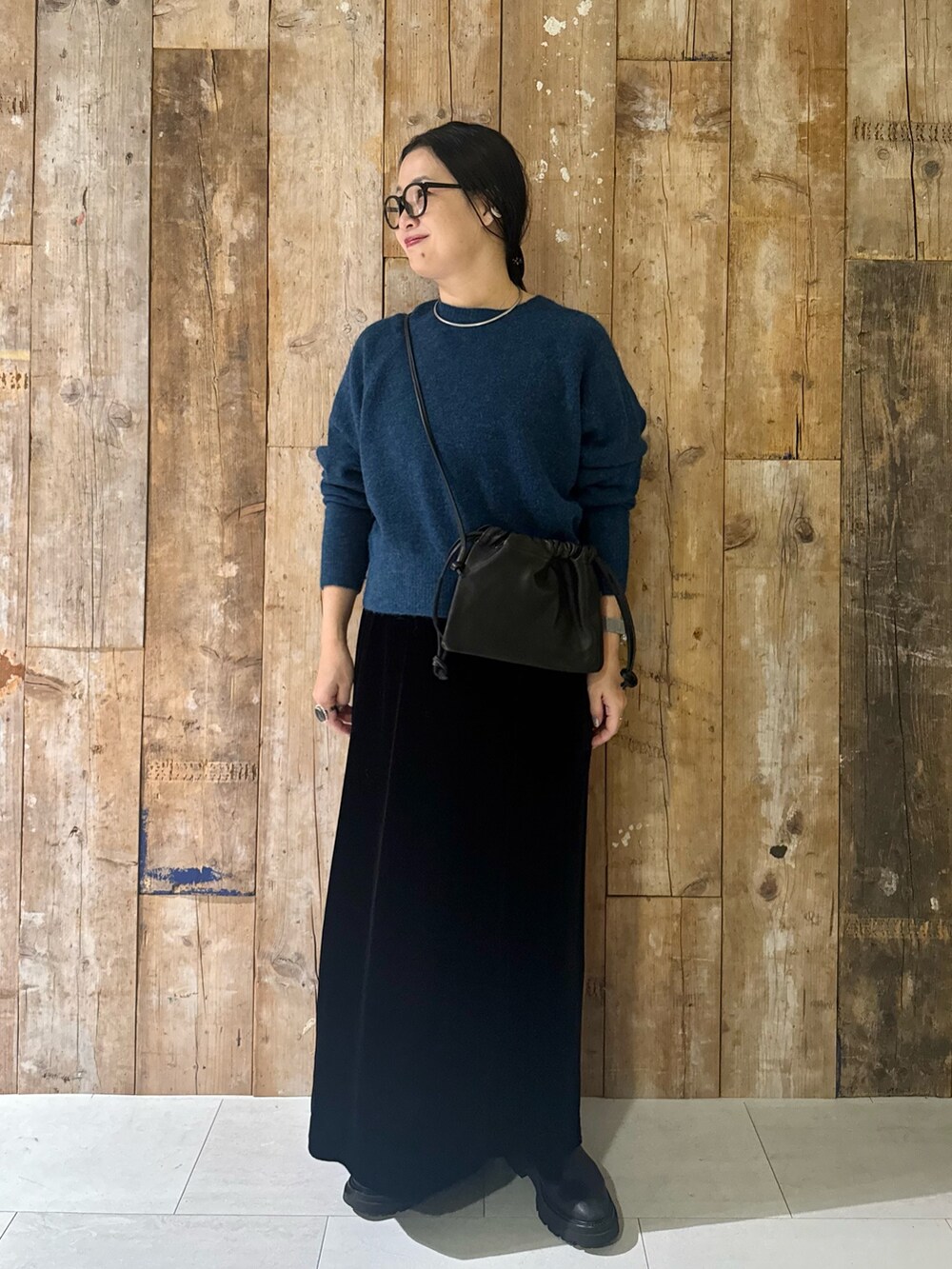 ブルー系のニット/セーター、ブラック系のスカート、ブラック系のショルダーバッグを着用したレディースの冬コーディネートの2枚目の写真