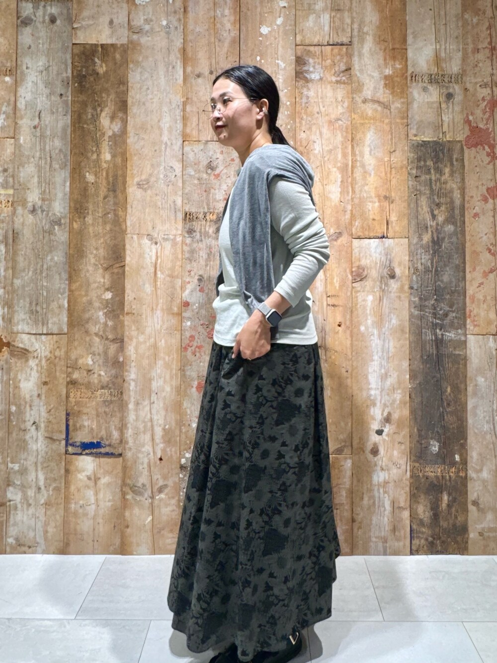 グレー系のカーディガン/ボレロ、グリーン系のTシャツ/カットソー、グレー系のスカートを着用したレディースの秋コーディネートの2枚目の写真