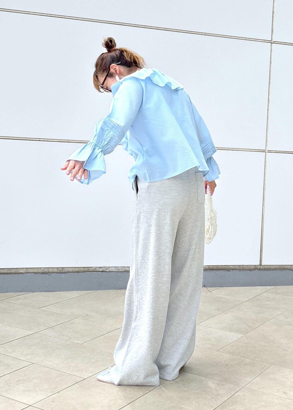 ブルー系のシャツ/ブラウス、グレー系のその他パンツ、ホワイト系のハンドバッグを着用したレディースの春コーディネートの4枚目の写真