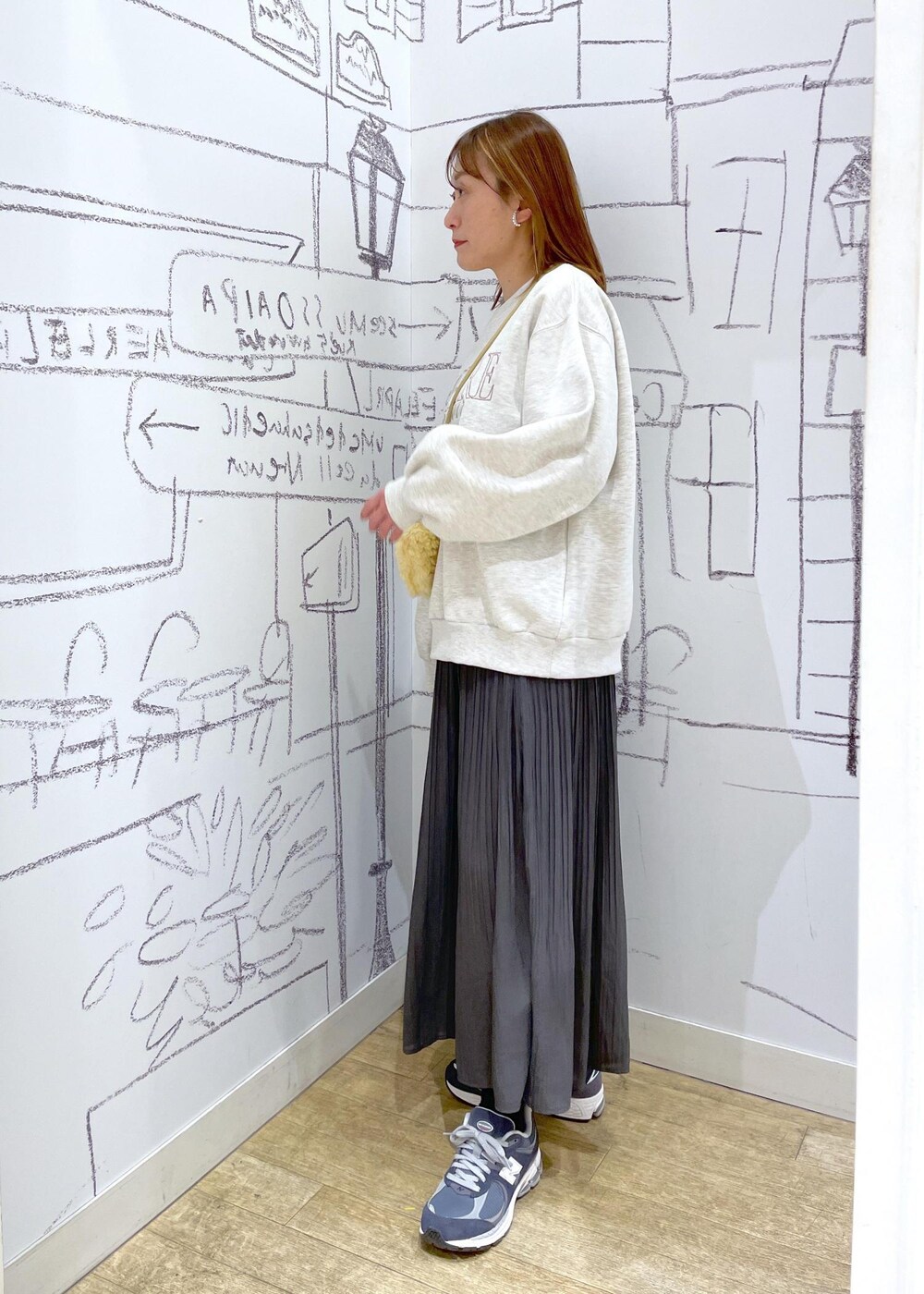 イエロー系のショルダーバッグ、ホワイト系のスウェット、グレー系のワンピースを着用したレディースの冬コーディネートの2枚目の写真