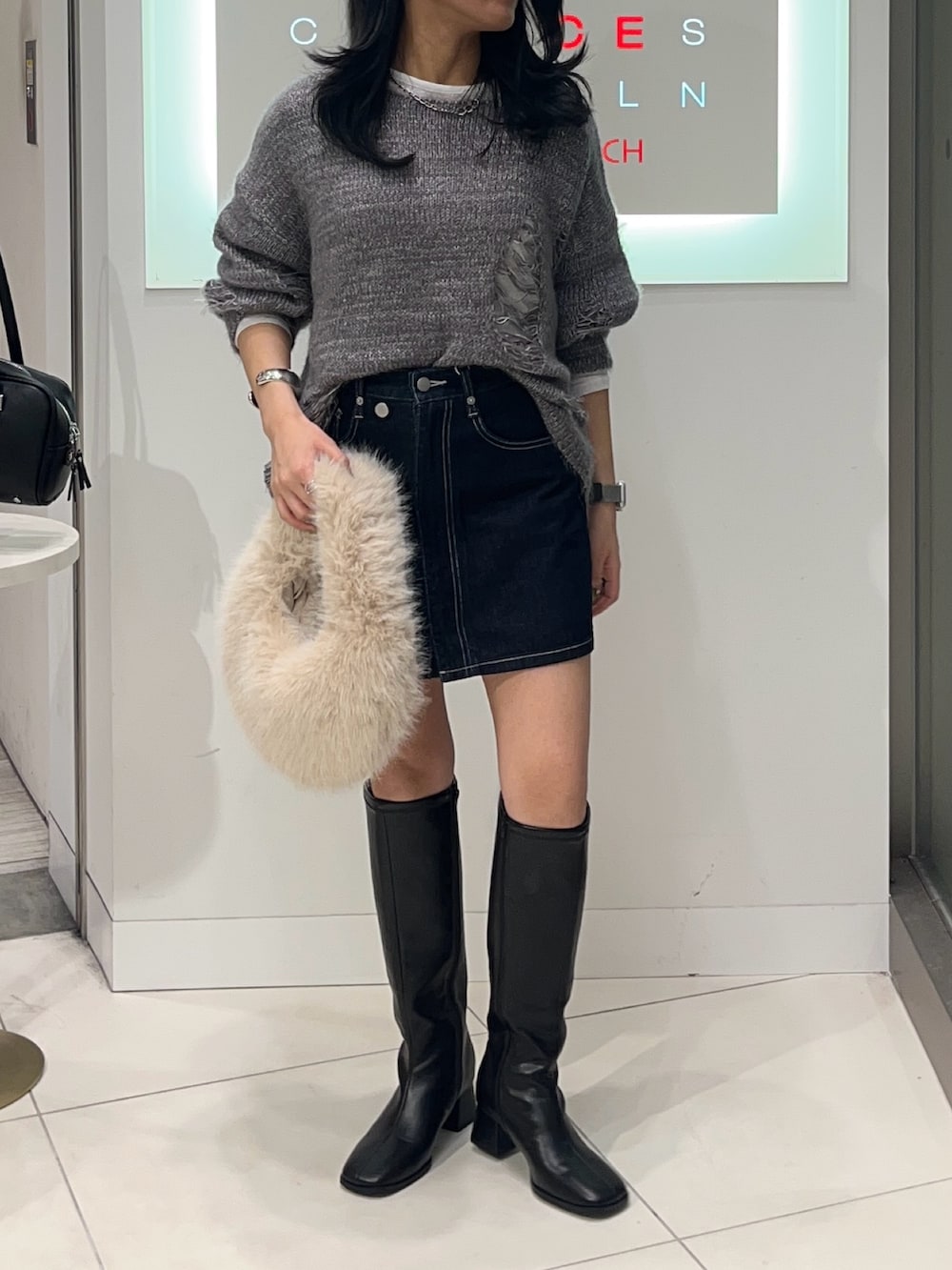 グレー系のニット/セーター、ブルー系のスカート、ホワイト系のTシャツ/カットソーを着用したレディースの秋コーディネートの2枚目の写真