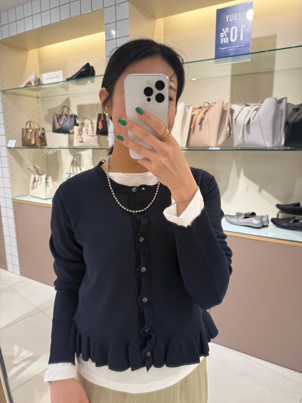 ブルー系のニット/セーター、ベージュ系のスカート、ホワイト系のTシャツ/カットソーを着用したレディースの春コーディネートの6枚目の写真