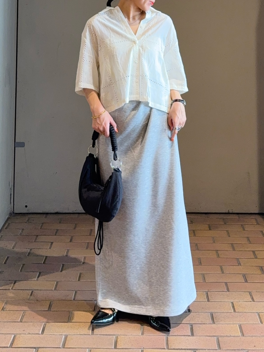 ホワイト系のシャツ/ブラウス、ブラック系のハンドバッグ、グレー系のスカートを着用したレディースの夏コーディネートの3枚目の写真