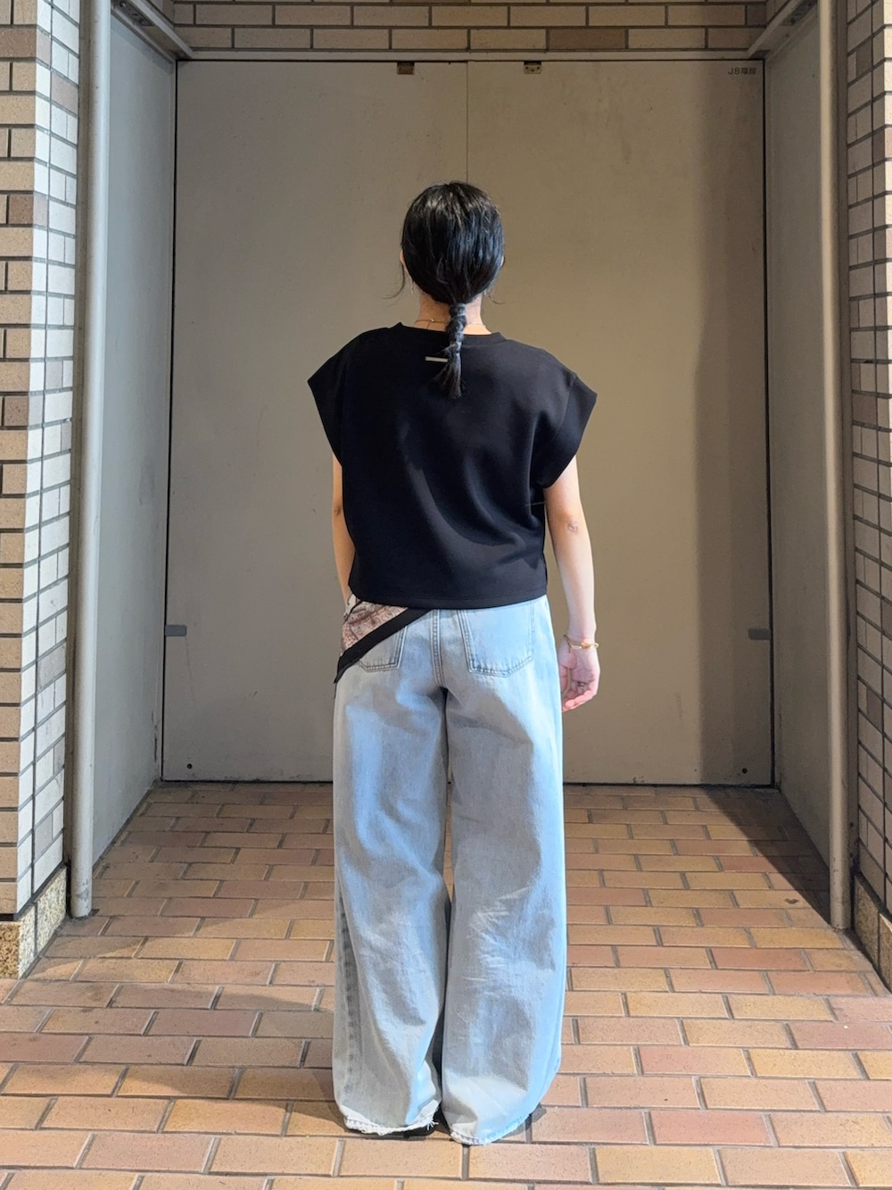 ブラック系のTシャツ/カットソー、ブルー系のデニムパンツ、ブラック系のパンプスを着用したレディースの夏コーディネートの3枚目の写真