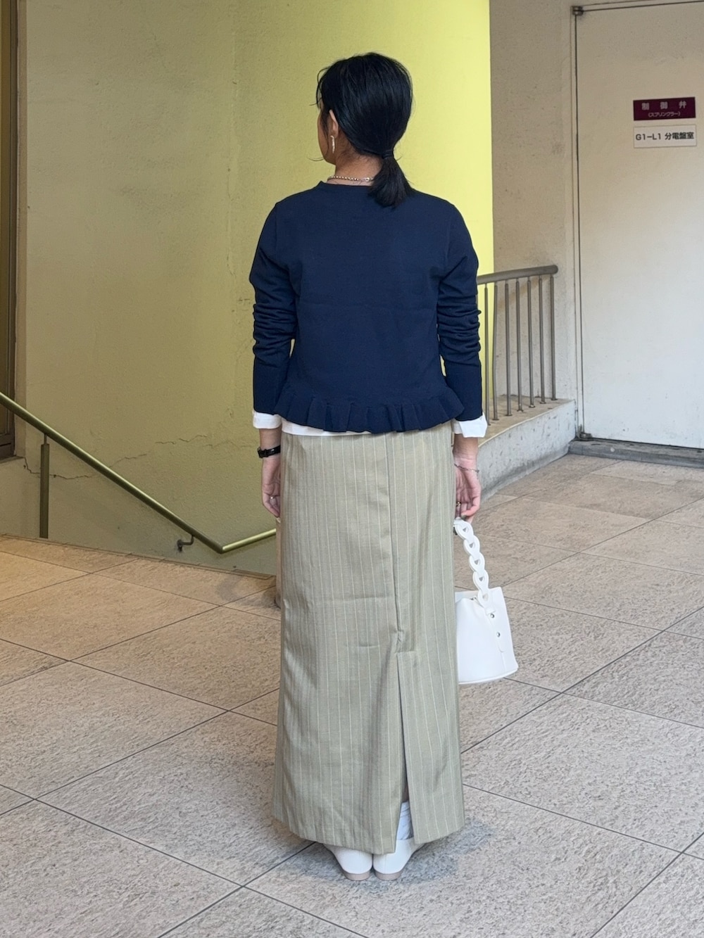 ブルー系のニット/セーター、ベージュ系のスカート、ホワイト系のTシャツ/カットソーを着用したレディースの春コーディネートの3枚目の写真