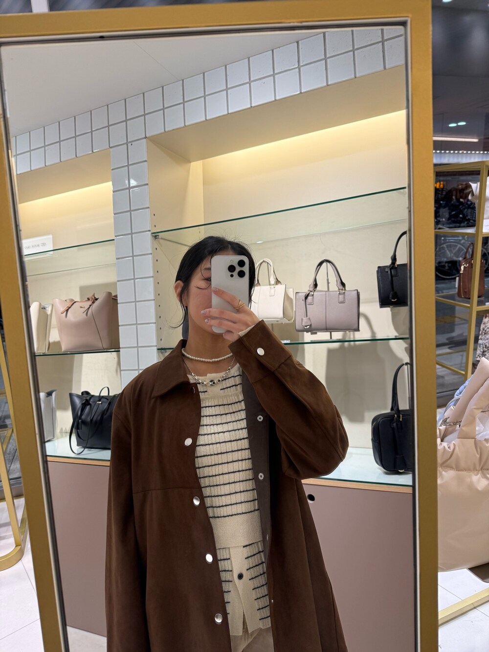 ブラウン系のその他アウター、ホワイト系のニット/セーター、ベージュ系のデニムパンツを着用したレディースの冬コーディネートの5枚目の写真