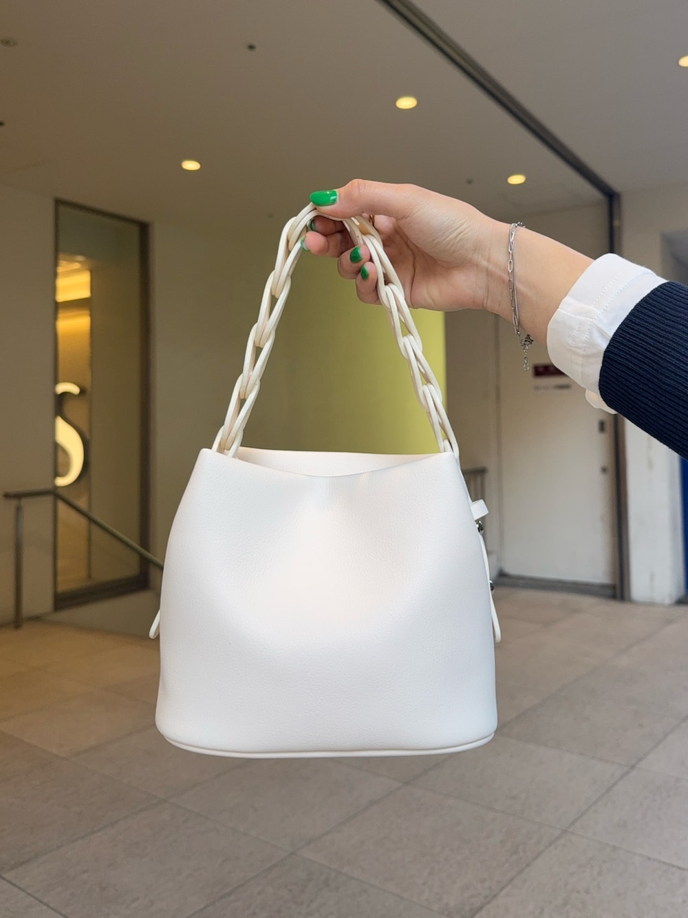 ブルー系のニット/セーター、ベージュ系のスカート、ホワイト系のTシャツ/カットソーを着用したレディースの春コーディネートの4枚目の写真