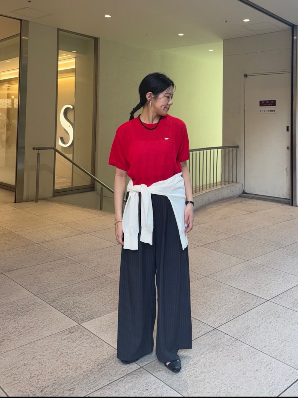 レッド系のニット/セーター、ホワイト系のカーディガン/ボレロ、グレー系のスラックスを着用したレディースの夏コーディネートの2枚目の写真