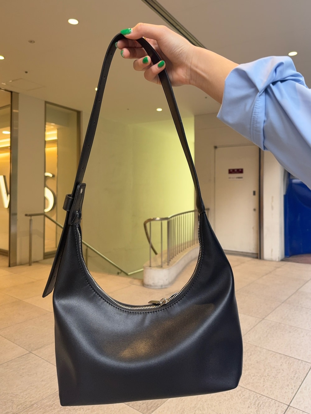 ベージュ系のスカート、ホワイト系のニット/セーター、ブルー系のシャツ/ブラウスを着用したレディースの春コーディネートの4枚目の写真