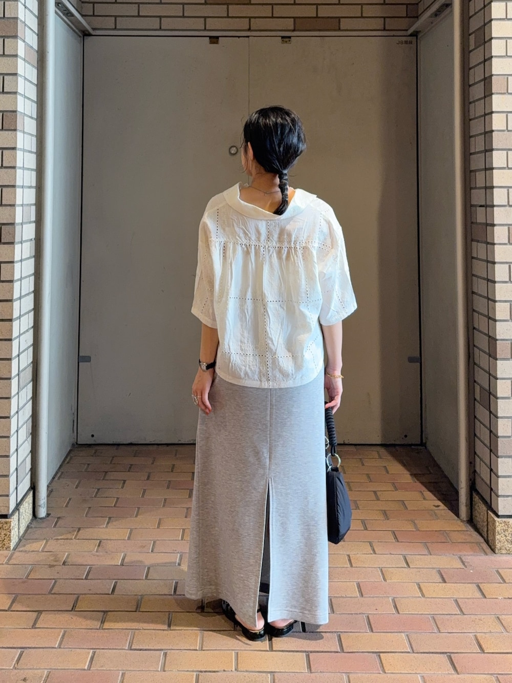 ホワイト系のシャツ/ブラウス、ブラック系のハンドバッグ、グレー系のスカートを着用したレディースの夏コーディネートの2枚目の写真