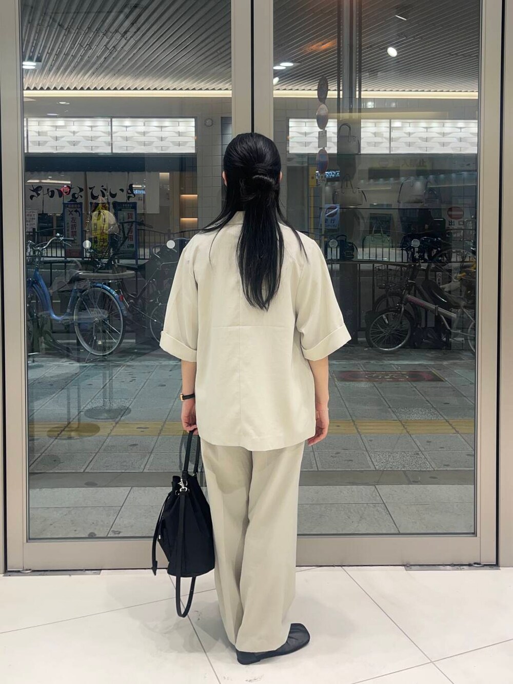 ブラック系のショルダーバッグ、ブラック系のパンプス、ホワイト系のTシャツ/カットソーを着用したレディースの春コーディネートの2枚目の写真