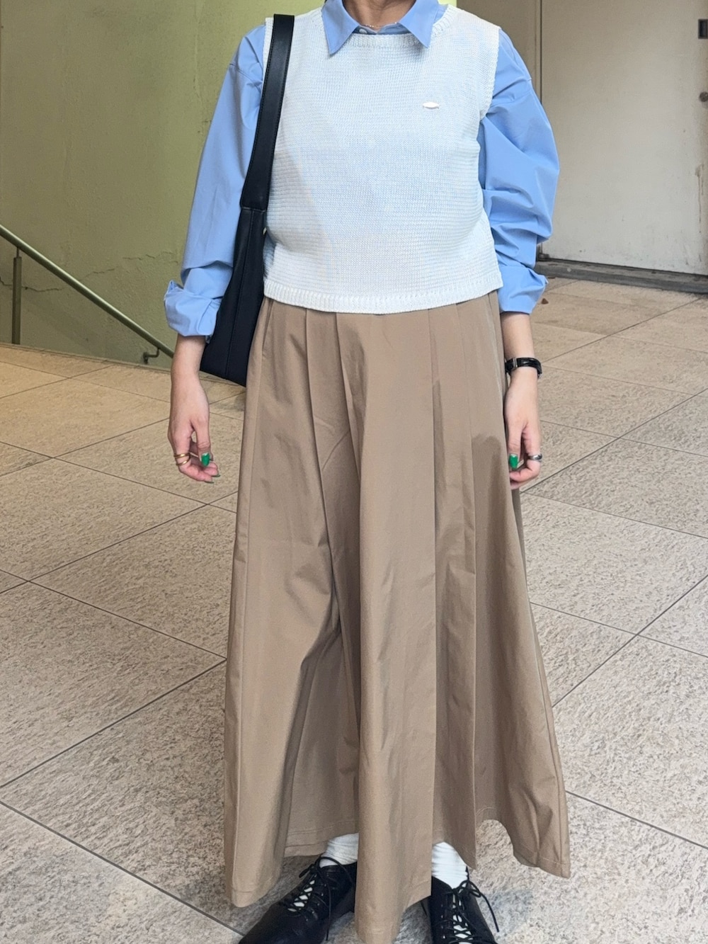 ベージュ系のスカート、ホワイト系のニット/セーター、ブルー系のシャツ/ブラウスを着用したレディースの春コーディネートの3枚目の写真