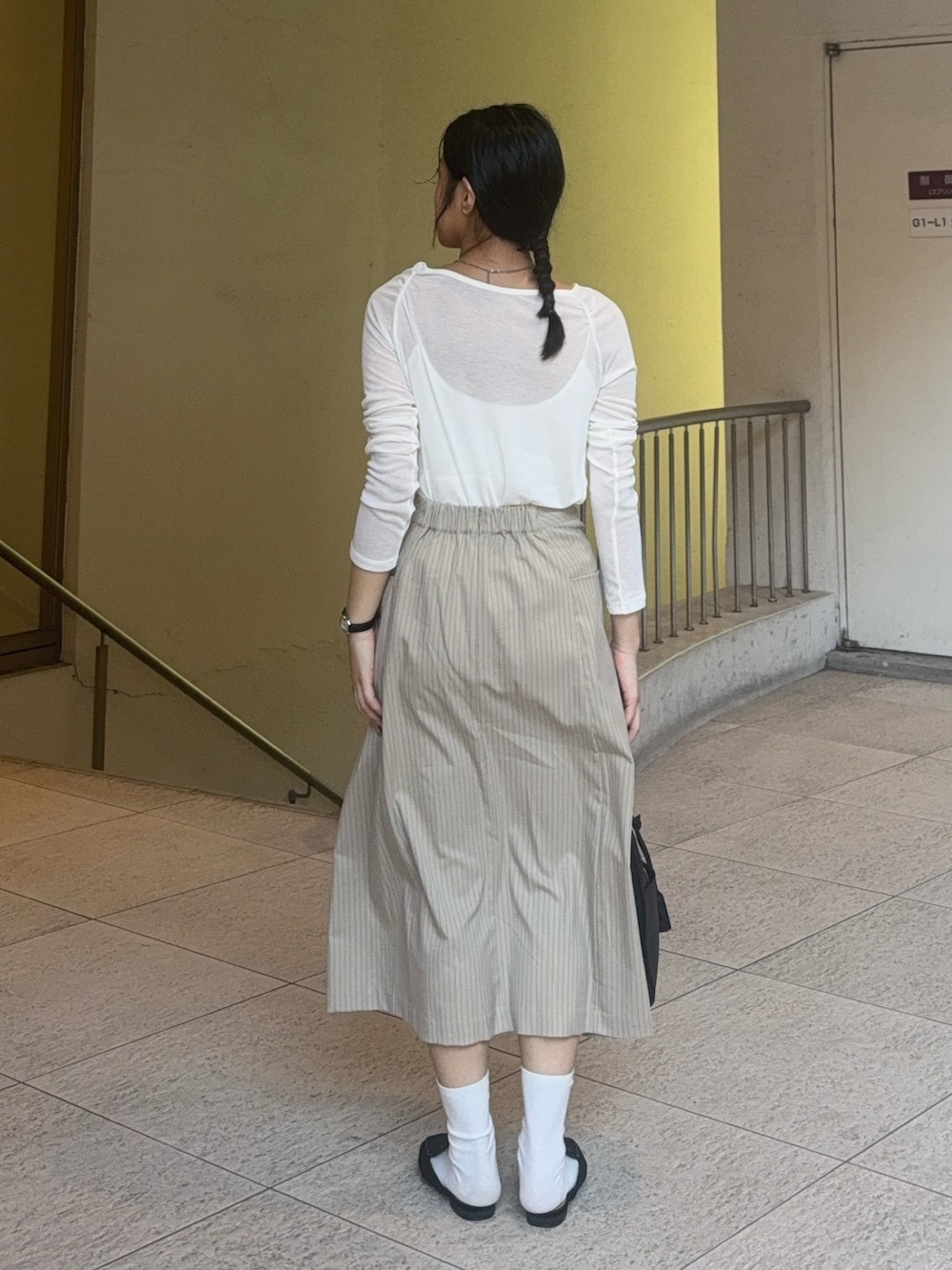 ホワイト系のTシャツ/カットソー、ベージュ系のスカート、ブラック系のその他シューズを着用したレディースの秋コーディネートの3枚目の写真