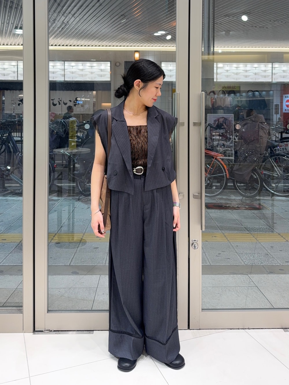 グレー系のその他パンツ、ブラック系のその他シューズ、ブラウン系のショルダーバッグを着用したレディースの夏コーディネートの2枚目の写真