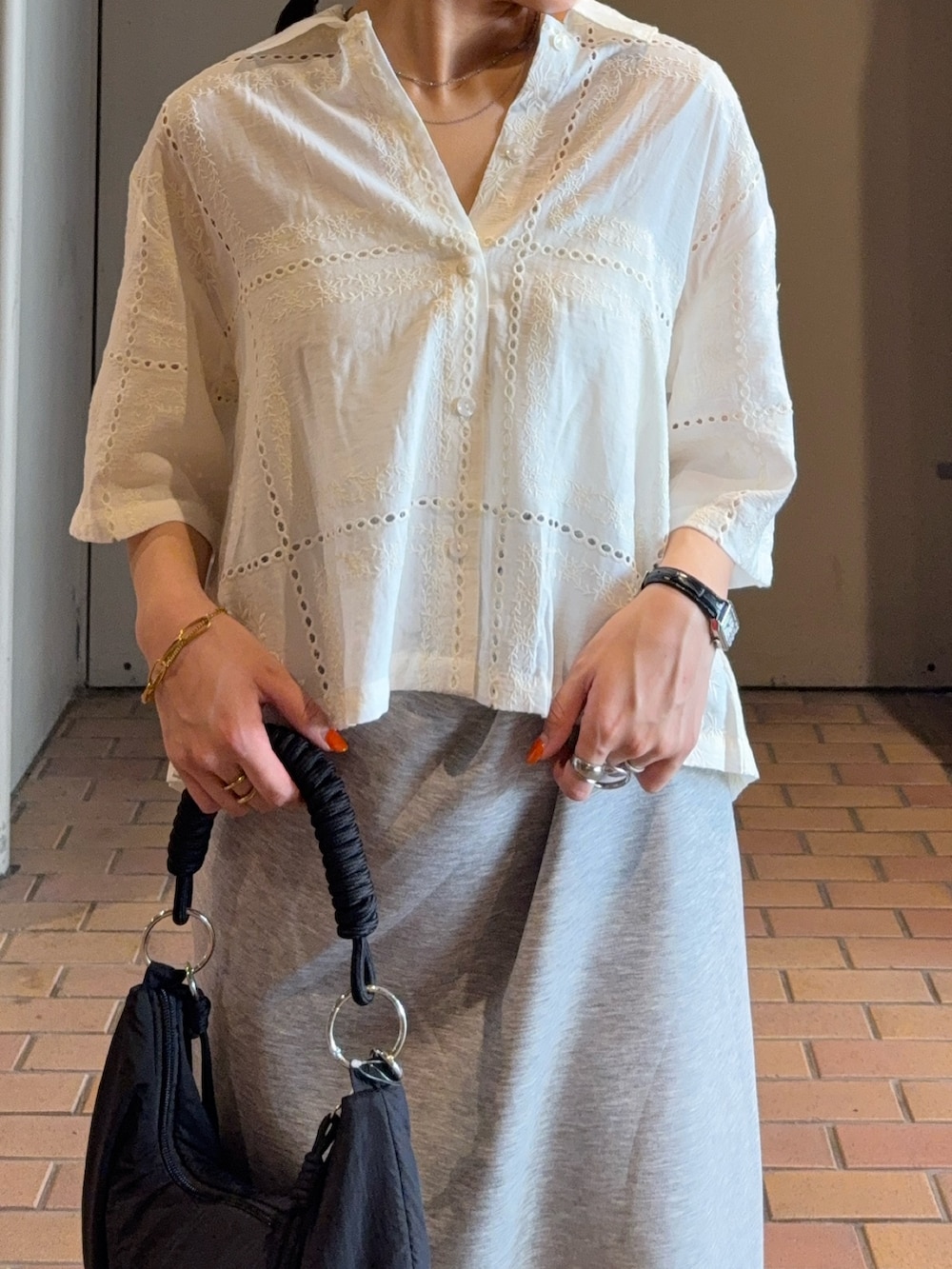 ホワイト系のシャツ/ブラウス、ブラック系のハンドバッグ、グレー系のスカートを着用したレディースの夏コーディネートの4枚目の写真