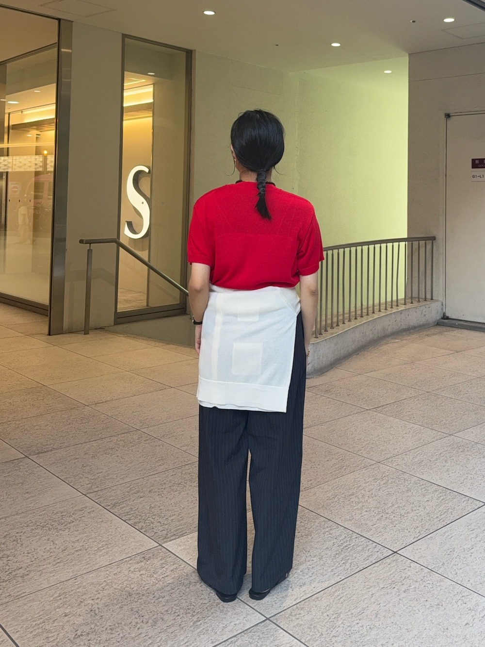 レッド系のニット/セーター、ホワイト系のカーディガン/ボレロ、グレー系のスラックスを着用したレディースの夏コーディネートの3枚目の写真