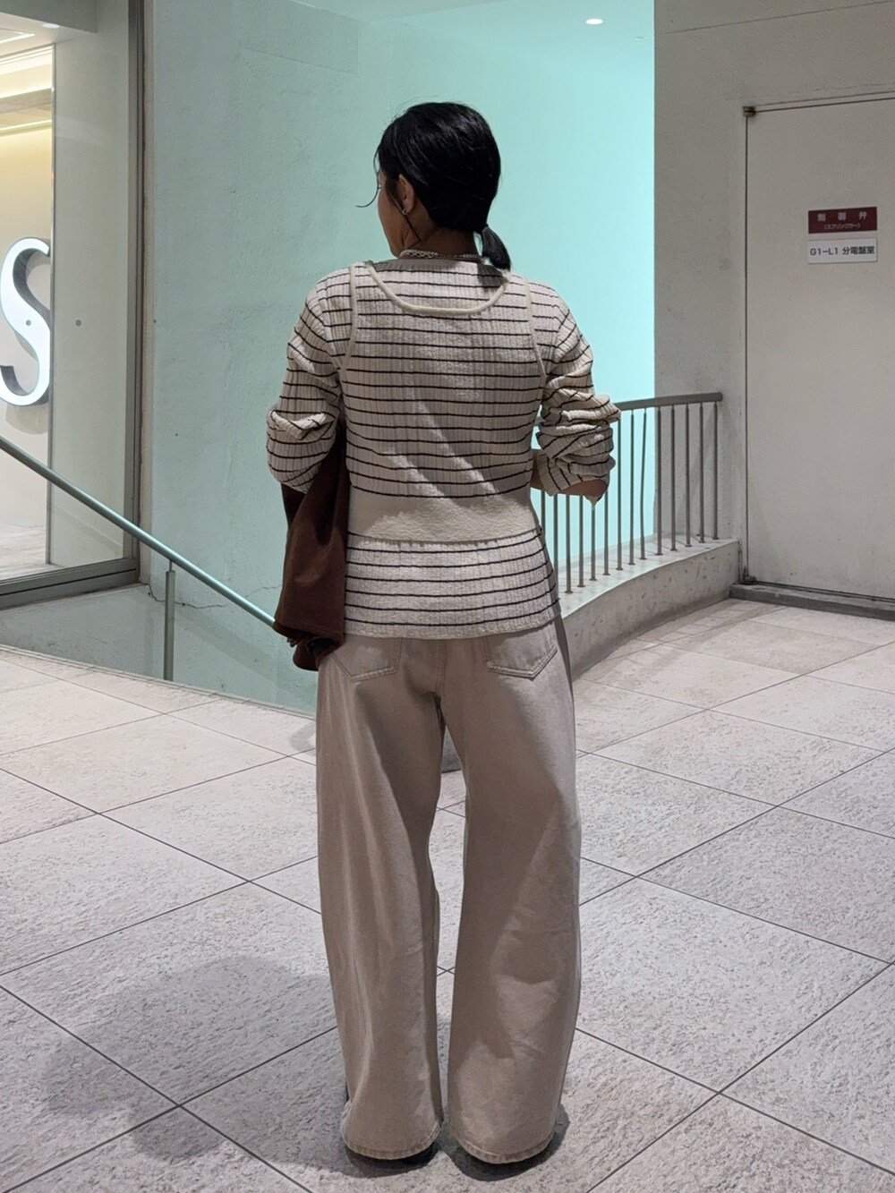 ブラウン系のその他アウター、ホワイト系のニット/セーター、ベージュ系のデニムパンツを着用したレディースの冬コーディネートの4枚目の写真