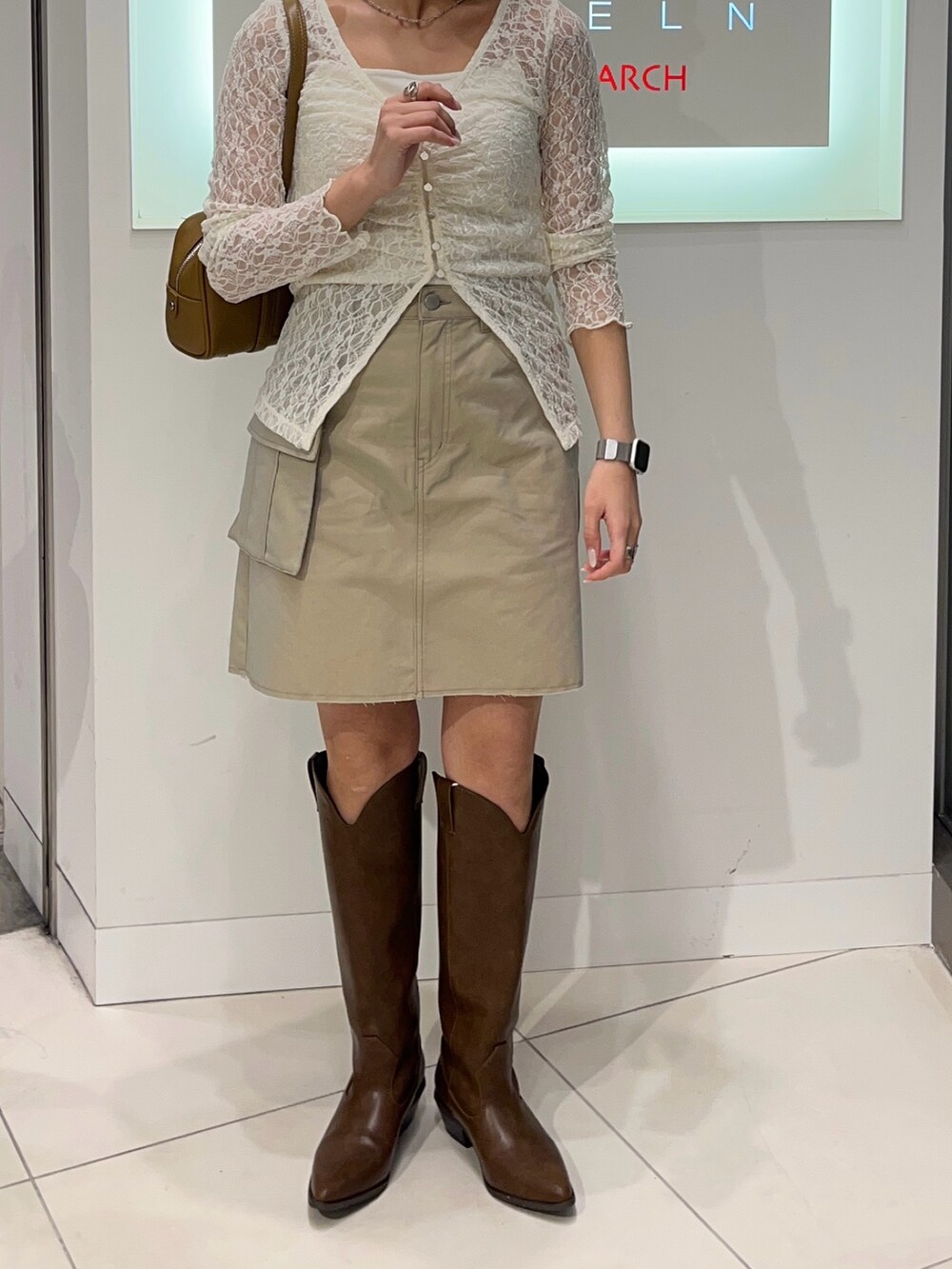 ホワイト系のTシャツ/カットソー、ベージュ系のスカート、ブラウン系のブーツを着用したレディースの秋コーディネートの2枚目の写真