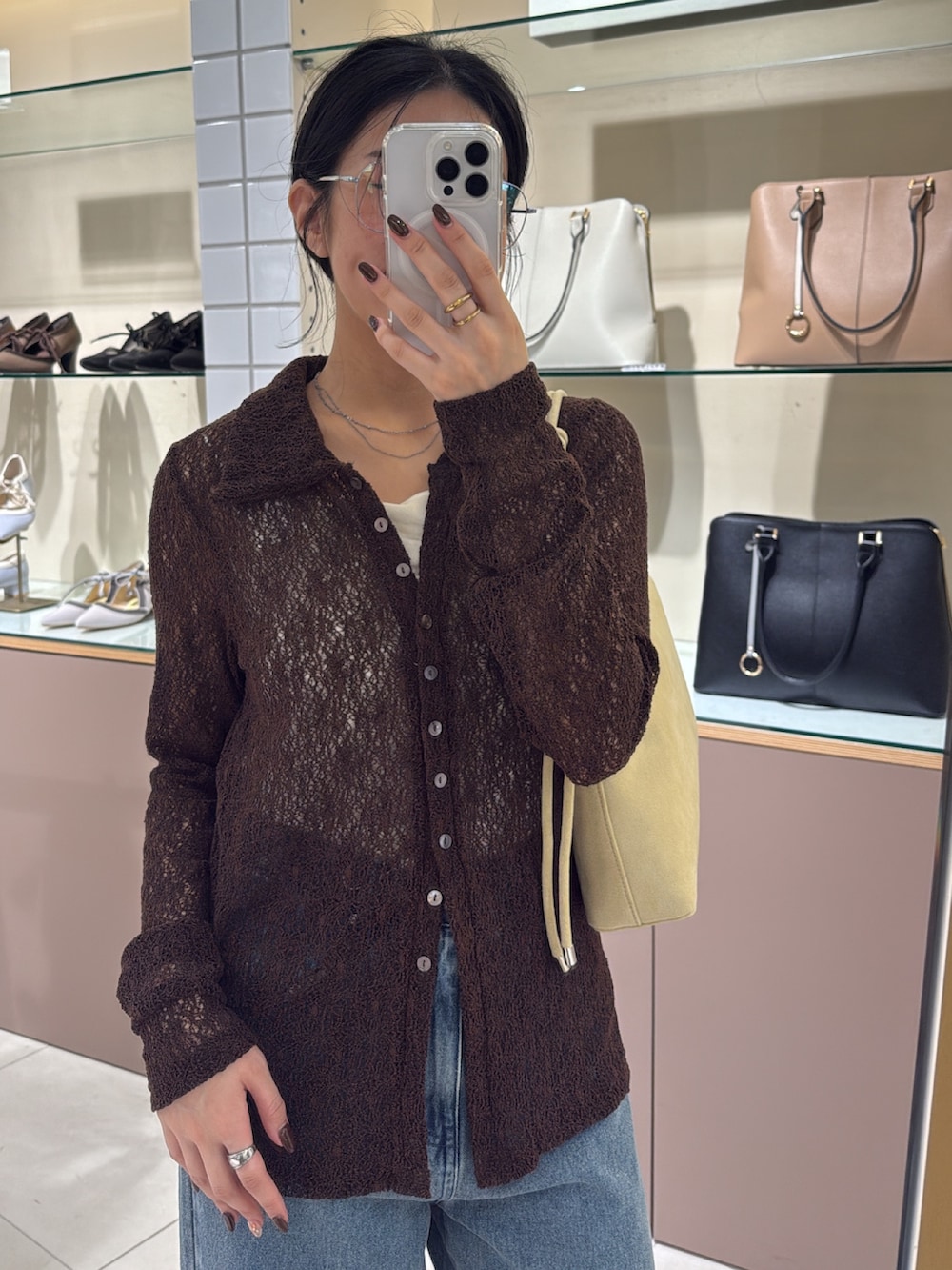 ベージュ系のハンドバッグ、ブルー系のデニムパンツ、ブラック系のその他シューズを着用したレディースの秋コーディネートの7枚目の写真
