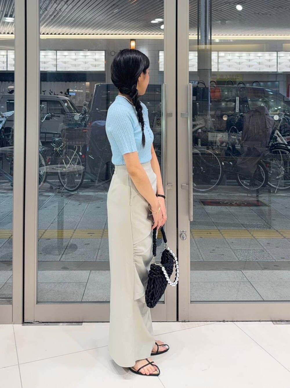 ブラック系のハンドバッグ、ホワイト系のキャミソール、ブラック系のサンダルを着用したレディースの夏コーディネートの2枚目の写真