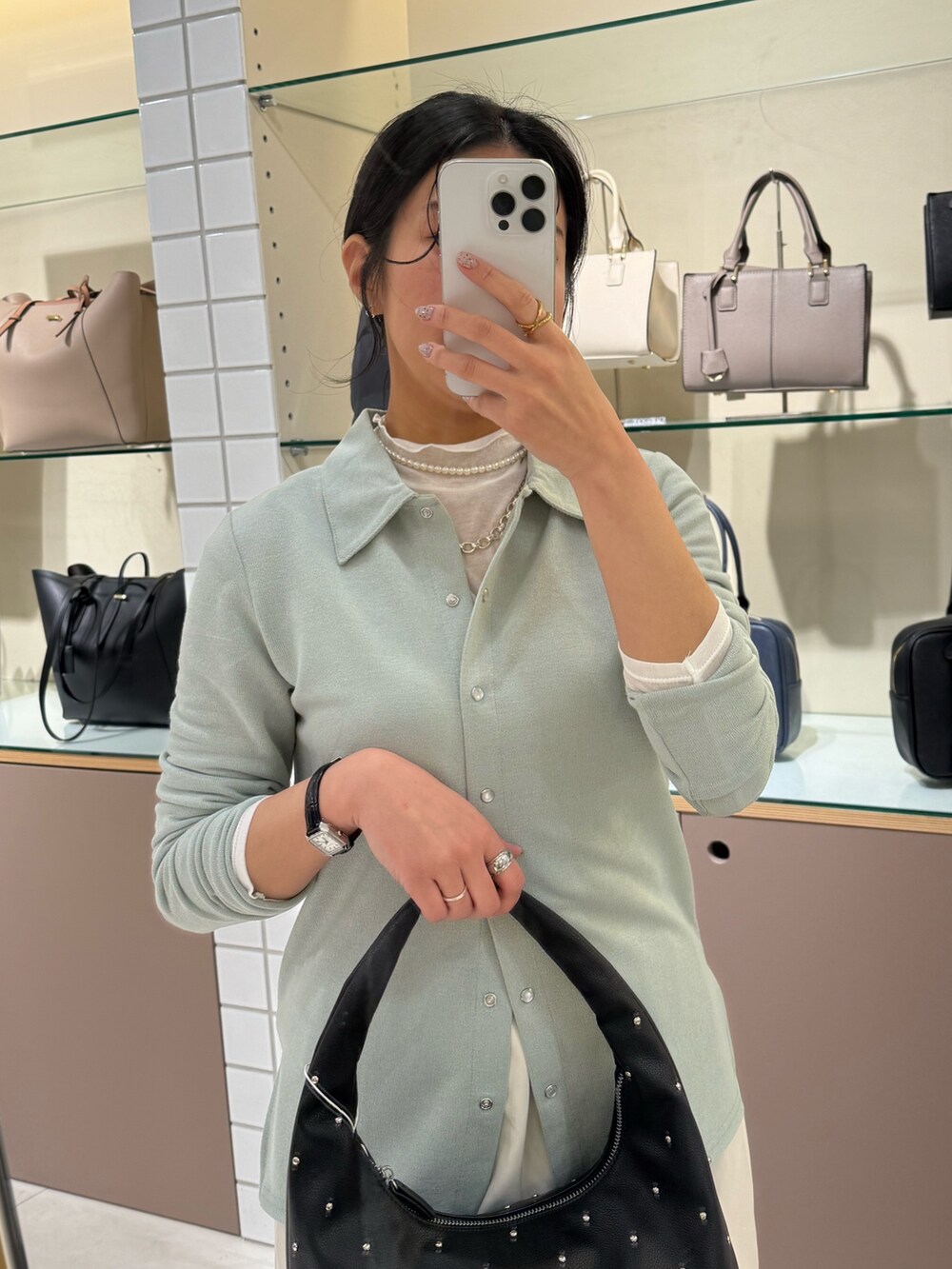 ホワイト系のスカート、ブラック系のローファー、ブラック系のハンドバッグを着用したレディースの冬コーディネートの3枚目の写真