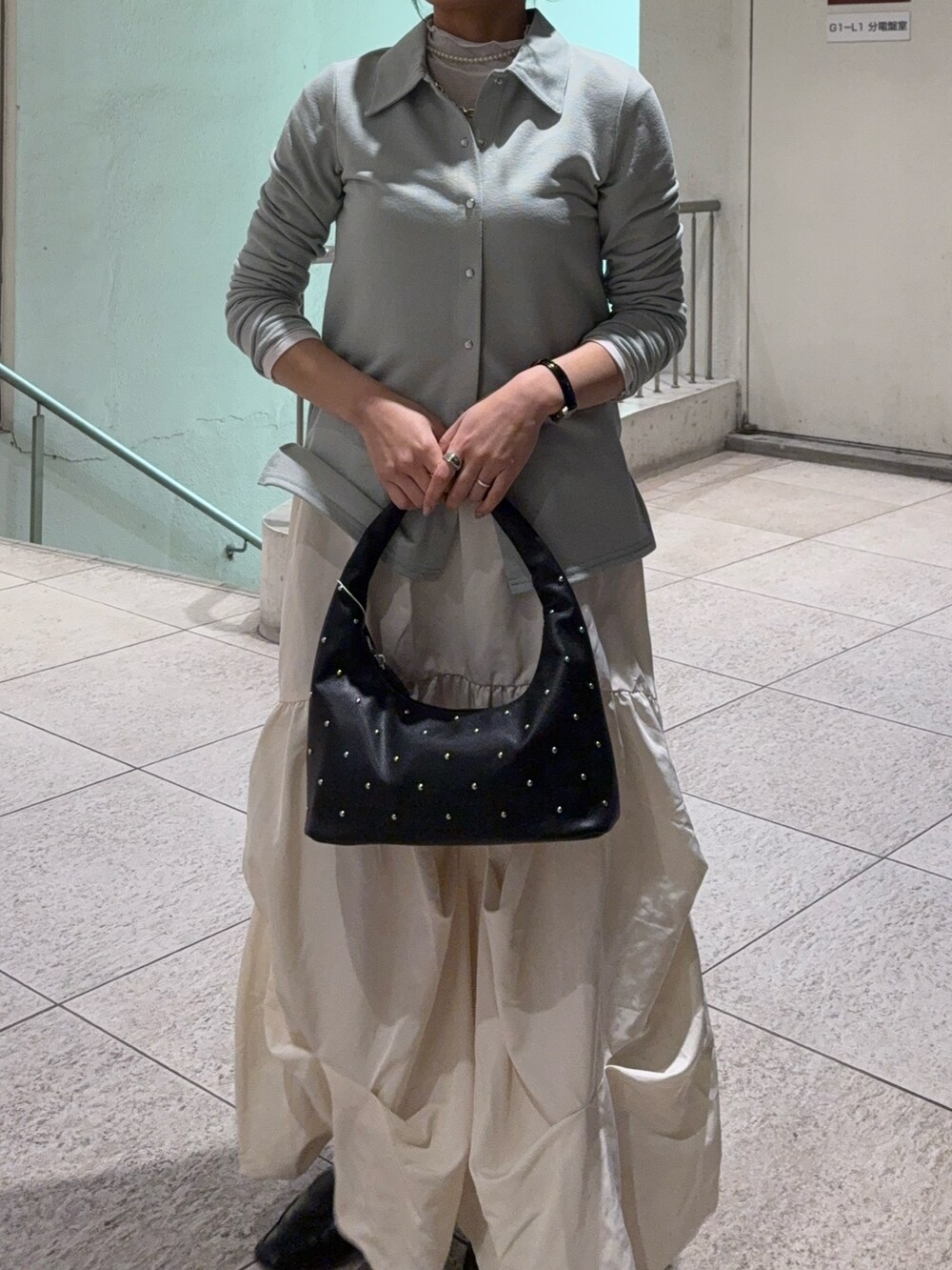 ホワイト系のスカート、ブラック系のローファー、ブラック系のハンドバッグを着用したレディースの冬コーディネートの2枚目の写真