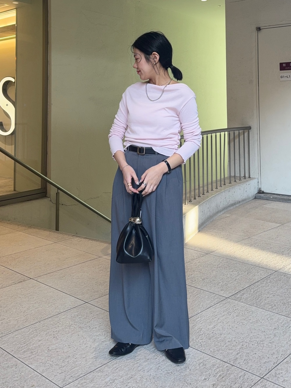 グレー系のスラックス、ブラウン系のハンドバッグ、ブラック系のローファーを着用したレディースの冬コーディネートの2枚目の写真